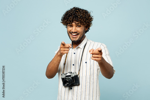 Traveler Indian man wears white casual clothes point index finger camera on you motivating isolated on plain blue background. Tourist travel abroad in free time rest getaway. Air flight trip concept. #785387236