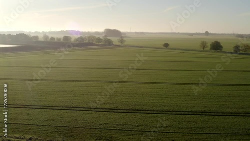 Aerial fly over panorama of beautiful English countryside farmlands and crop fields in hazy autumn morning condition and countryside road outdoors. Copy space sky background 