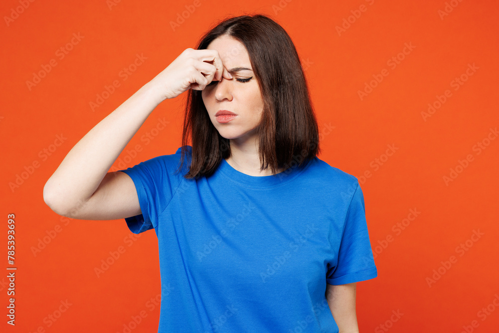 Young sad sick ill frustrated exhausted woman she wearing blue t-shirt casual clothes keep eyes closed rub put hand on nose isolated on plain red orange background studio portrait. Lifestyle concept. Young sad sick ill frustrated exhausted woman she wearing blue t-shirt casual clothes keep eyes closed rub put hand on nose isolated on plain red orange background studio portrait. Lifestyle concept.