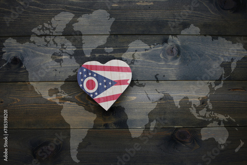 wooden heart with national flag of ohio state near world map on the wooden background.