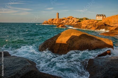 Lighthouse of Ploumanach at the golden hour in Perros-Guirec, Côtes d'Armor, Brittany, France. Sea tide, waves, lighthouse in the background. © Ivan