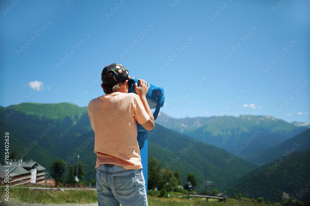 boy observing mountains panorama through stationary binoculars