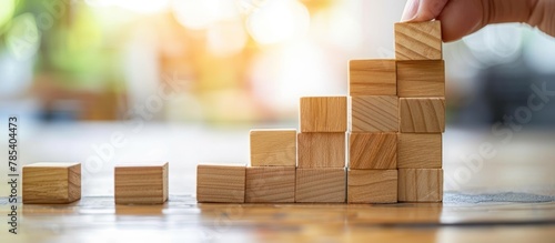 A man's hand gently stacks the wooden blocks, with the steps facing up. the concept of growth and success