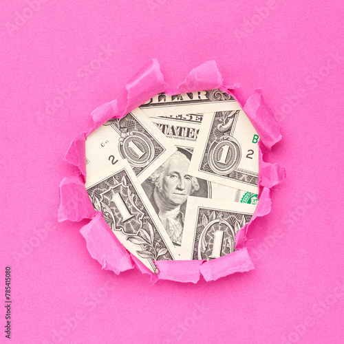US dollars bills in the hole of pink paper