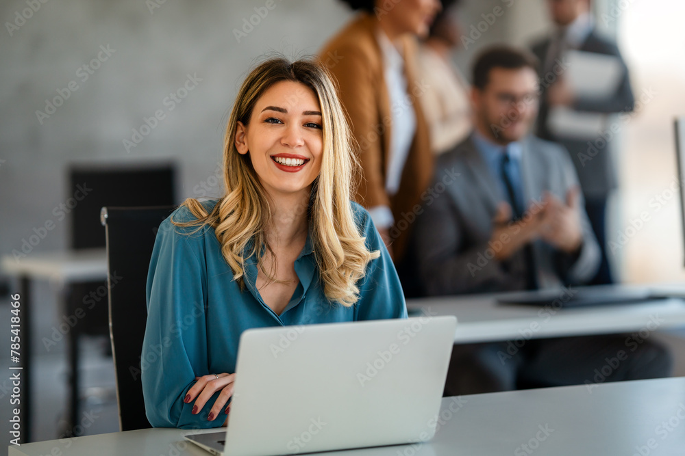 Fototapeta premium Young happy successful business woman working with laptop in corporate office