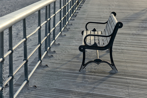 bench on the boardwalk at the beach (jones beach state park on long island nassau county new york) railing with wooden planks and sand (empty, no people) summer relaxation recreation getaway