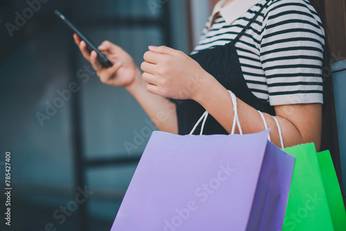 A woman is holding a cell phone and shopping bags