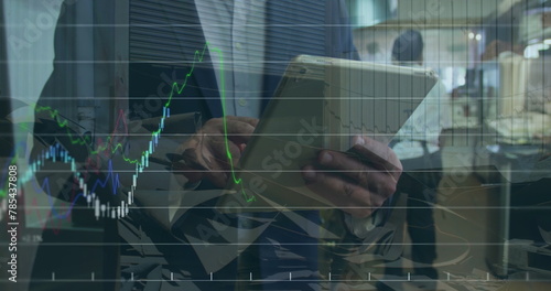 Image of financial data and graphs over hands of caucasian businessman using tablet