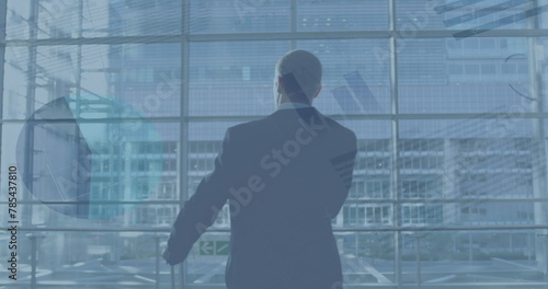 Image of financial graphs over back view of caucasian businessman with suitcase