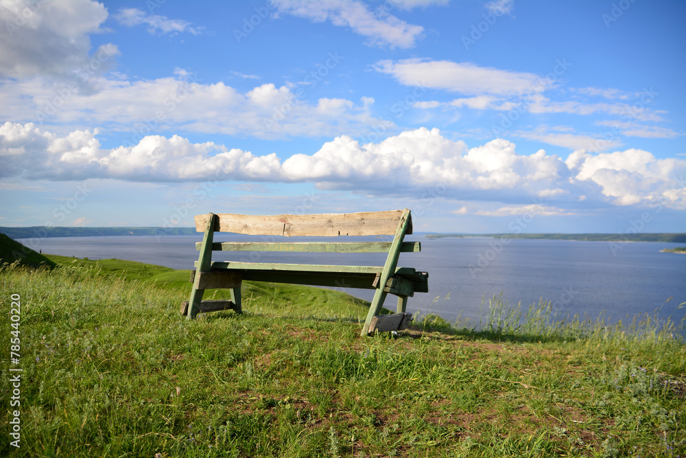 Obraz premium a wooden bench on the edge of the hill with cloudscape on background 