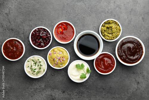 Different tasty sauces in bowls on grey table, flat lay