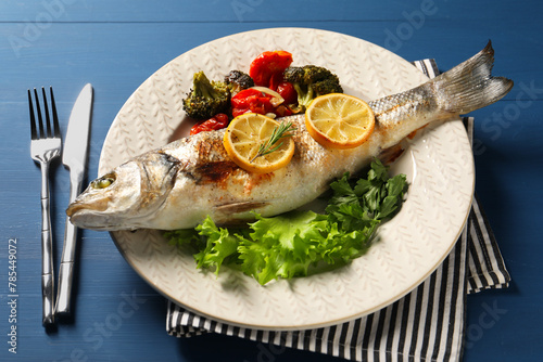 Delicious baked fish and vegetables served on blue wooden table