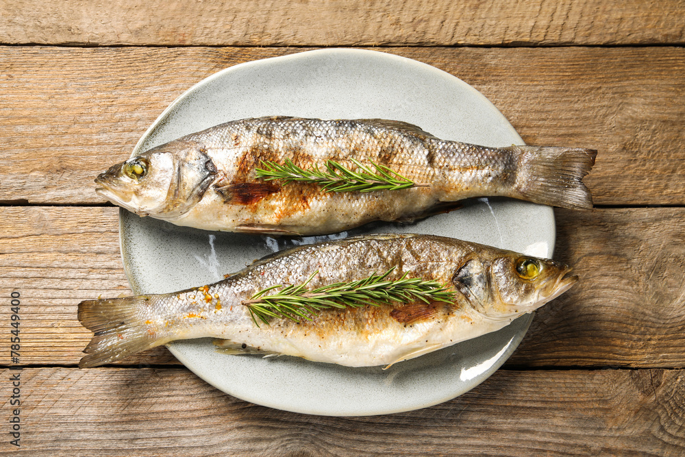 Delicious baked fish and rosemary on wooden table, top view Delicious baked fish and rosemary on wooden table, top view