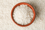 Raw basmati rice and bowl as background, top view