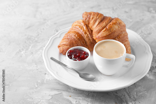 Tasty breakfast. Cup of coffee, fresh croissants and jam on grey table, space for text