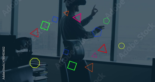 Image of colorful geometric shapes over caucasian businessman gesturing while vr headset
