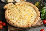 Delicious cheese pizza and ingredients on dark grey table