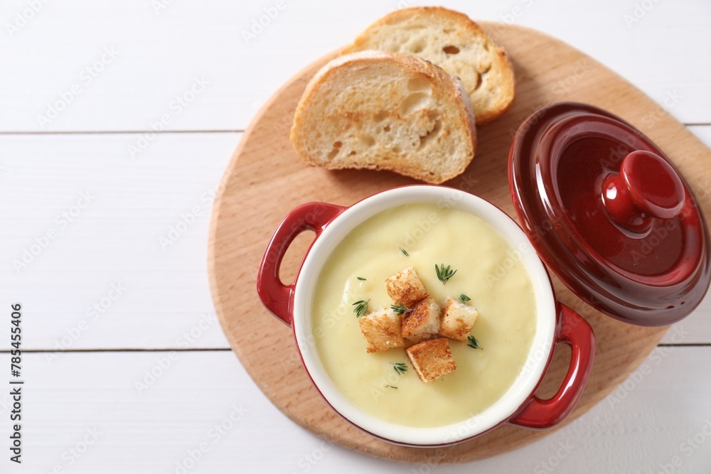 Tasty potato soup with croutons and rosemary in ceramic pot on white wooden table, flat lay. Space for text Tasty potato soup with croutons and rosemary in ceramic pot on white wooden table, flat lay. Space for text