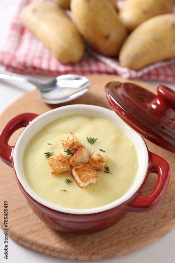 Tasty potato soup with croutons and rosemary in ceramic pot on white table, closeup Tasty potato soup with croutons and rosemary in ceramic pot on white table, closeup
