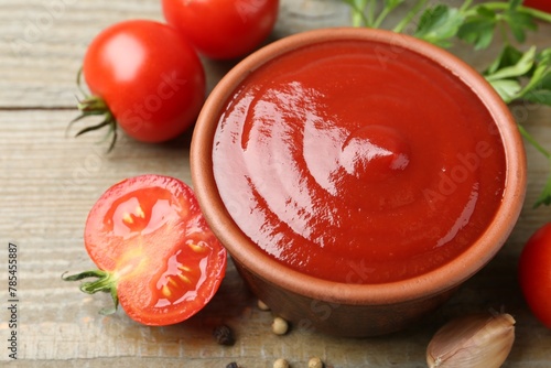 Fototapeta Naklejka Na Ścianę i Meble -  Tasty ketchup, fresh tomatoes, parsley and spices on wooden table, closeup