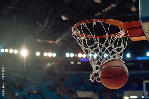 Close-up of a basketball going through the hoop in an arena.