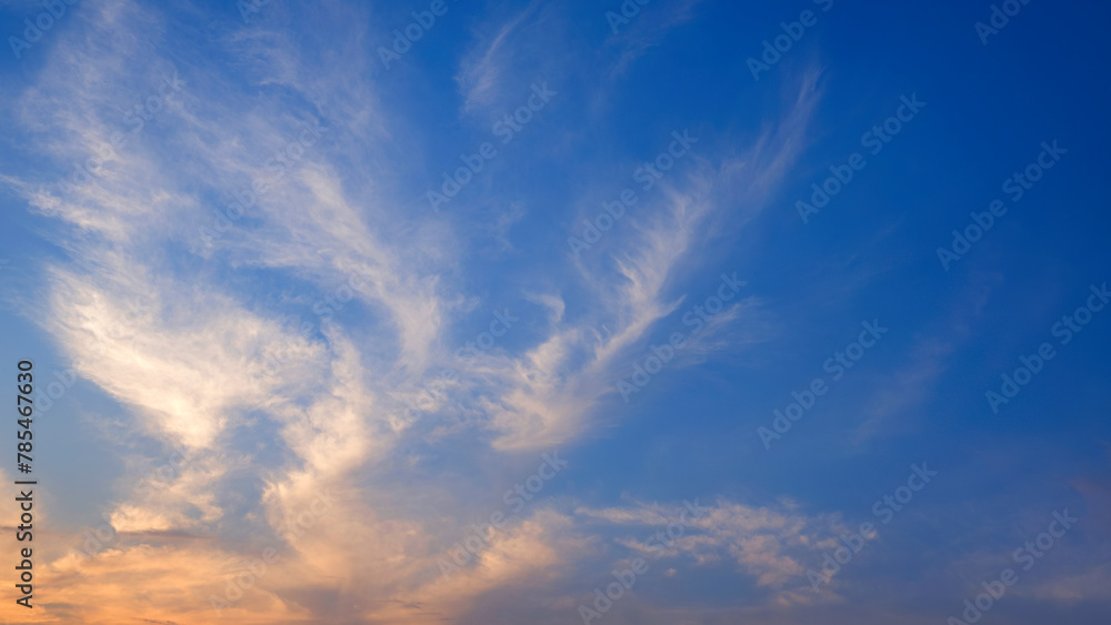Sunset sky with orange sunlight and softly cloud streaks look like mask shaped on horizon dusk blue sky background in the evening