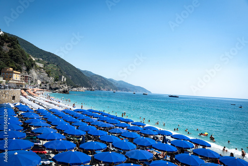 Cinque Terre, Italy - August 17 2023: Cinque Terre Monterosso seashore with trees, sea and mountains in the background