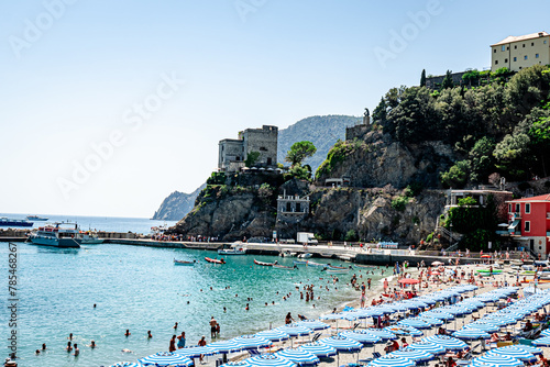 Cinque Terre, Italy - August 17 2023: Cinque Terre Monterosso seashore with trees, sea and mountains in the background
