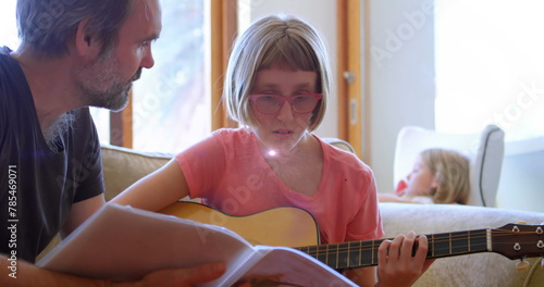 Image of light flashing over caucasian father learning daughter how to play guitar