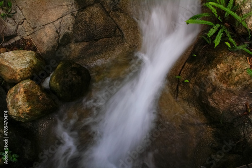 Close-up view of small waterfall into pond in rural in Hong Kong with slow shutter. Waterfall cascading gently over stones in forest. Nature scene. 