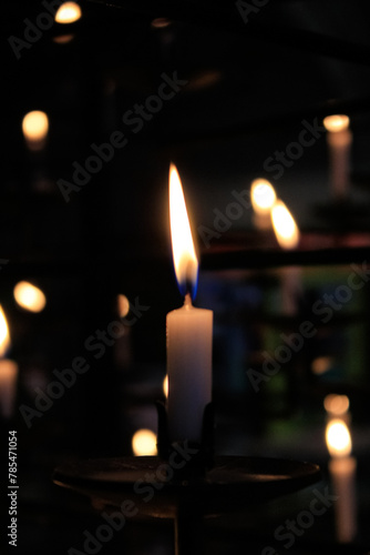 Close-up of the flame of candle in the dark in church with bokeh background. Candle light with copy space.