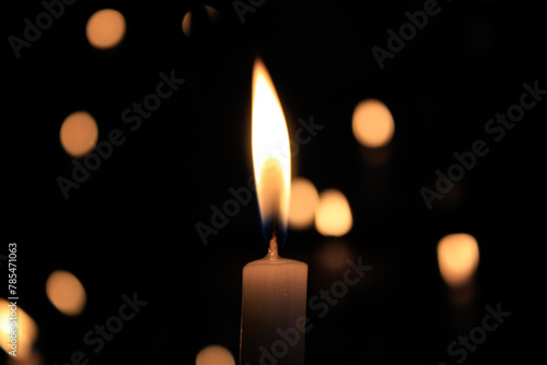 Close-up of the flame of candle in the dark in church with bokeh background. Candle light with copy space.