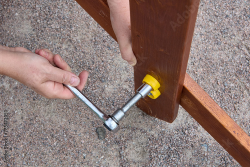 Tightening mounting bolt with ratchet socket wrench when assembling outdoor furniture. photo