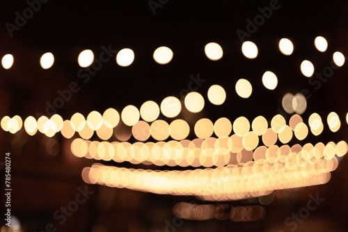 Christmas lights on the street blurred background, hung garlands with yellow lights