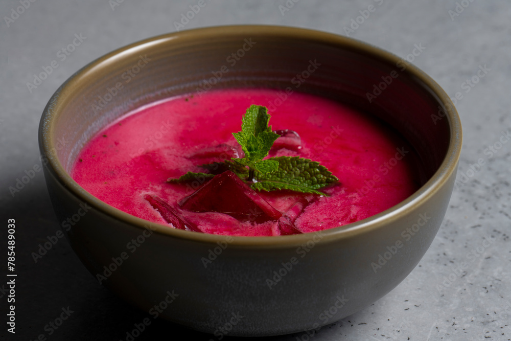 Cold beetroot soup with mint in a bowl on a gray background Cold beetroot soup with mint in a bowl on a gray background