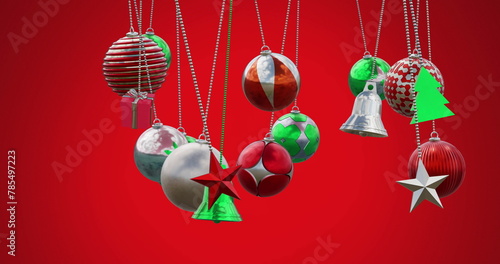Image of multicolored baubles, stars and bells swinging against red background