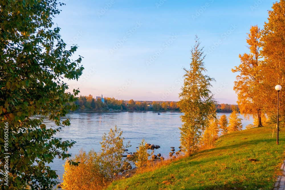 Colorful autumn landscape with birch grove with golden foliage on the shore of the lake and beautiful reflections at sunset. High quality photo