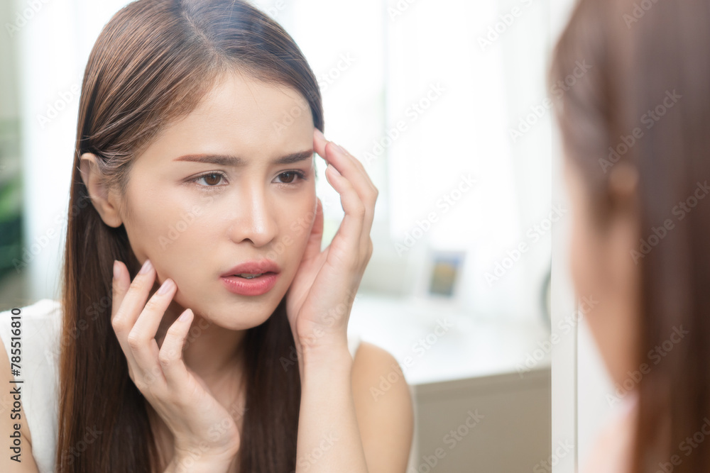 Anti aging, worry puberty asian young woman, stressed girl looking in mirror, allergy presenting an allergic reaction from cosmetic on face. Beauty, health care from acne problem, dry skin, treatment Anti aging, worry puberty asian young woman, stressed girl looking in mirror, allergy presenting an allergic reaction from cosmetic on face. Beauty, health care from acne problem, dry skin, treatment