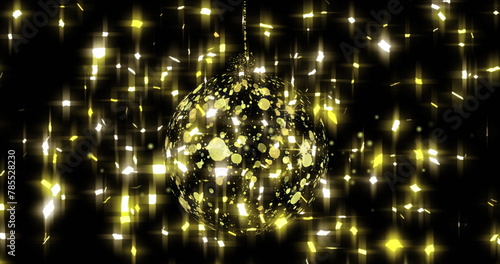 Image of stars falling over golden bauble on black background