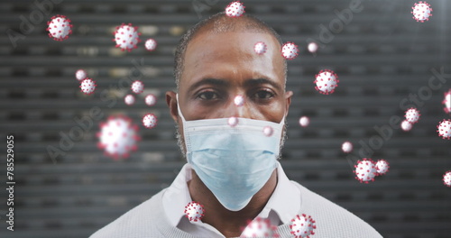 Image of covid 19 cells over african american man wearing face mask photo