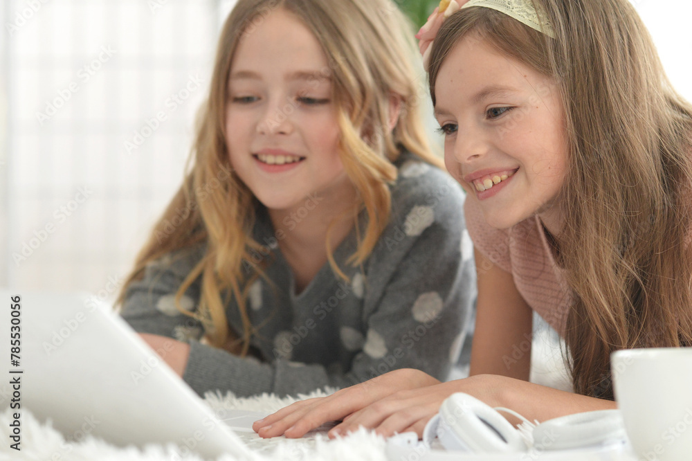 Fototapeta premium Two cute little girls with a laptop
