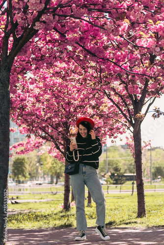pretty smiling woman posing in front of blooming sakura trees © phpetrunina14