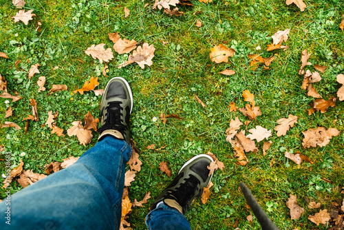 men legs standing on grass field covered with autumn oak leaves