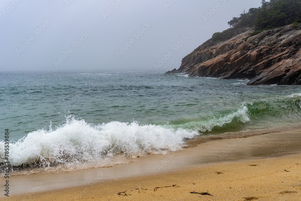 Crashing waves on Sand Beach in Acadia National Park, Maine. Surrounded by cliffs, this small stretch of coast is the largest sandy beach in Acadia. Rough surf on foggy, stormy day.