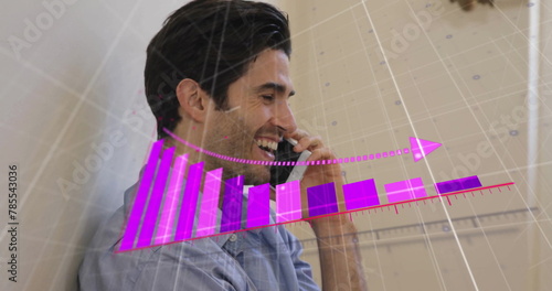 Image of arrow on falling graph and grid pattern over caucasian man talking on smartphone