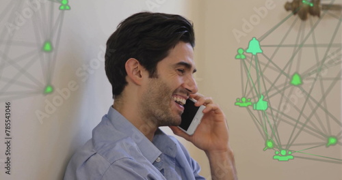 Image of connected icons forming globes over smiling caucasian man talking using cellphone
