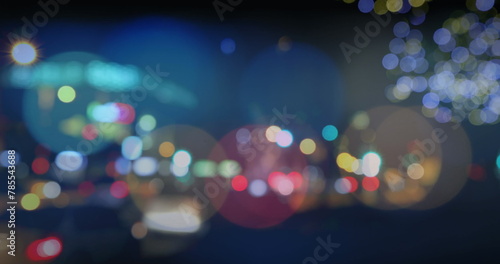 Image of road traffic in city at night with blurred city lights and colourful spots of light in the 