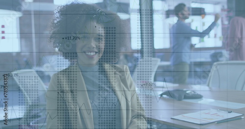 Image of charts and data processing over smiling biracial businesswoman in office