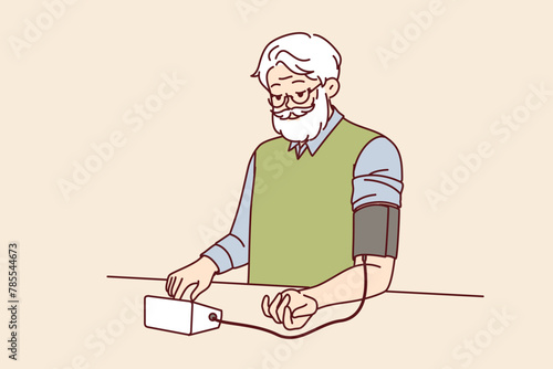 Elderly man measures blood pressure with tonometer, tracking health and cardio indicators. Gray-haired grandfather uses tonometer to decide whether to take pills prescribed by doctor or not.