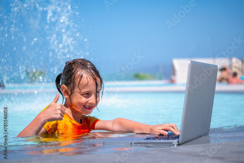 Distance Learning   Learning and study everywhere and always. Portrait of young girl learning with laptop computer in the swimming pool water.